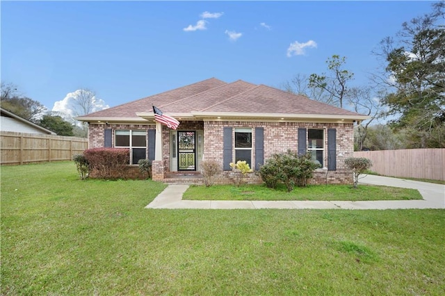 view of front facade featuring brick siding, roof with shingles, a front lawn, and fence