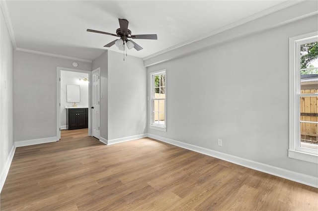 unfurnished bedroom with baseboards, light wood-style floors, crown molding, and multiple windows