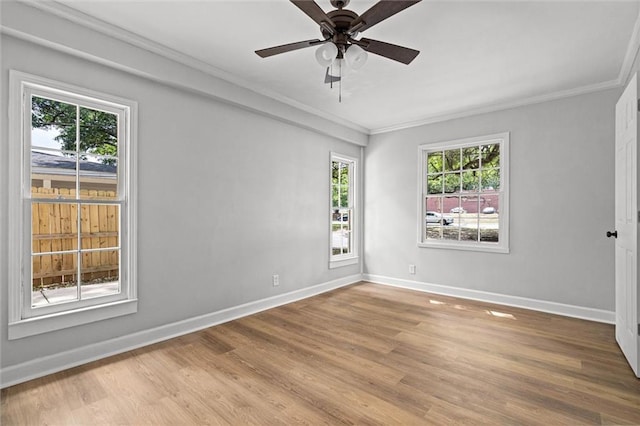 empty room featuring baseboards, ornamental molding, wood finished floors, and plenty of natural light