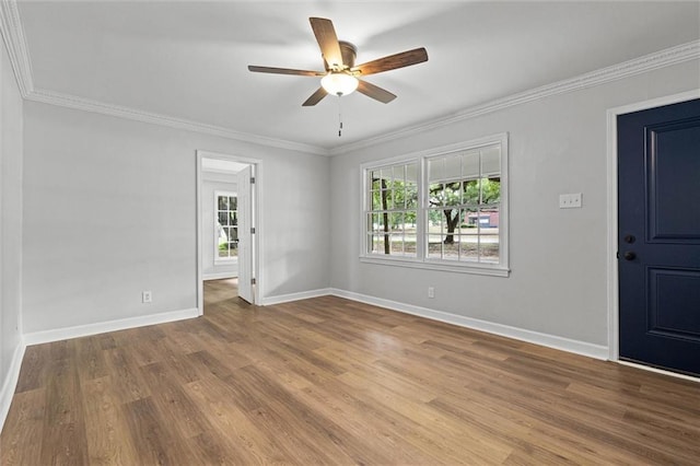 spare room featuring crown molding, baseboards, ceiling fan, and wood finished floors