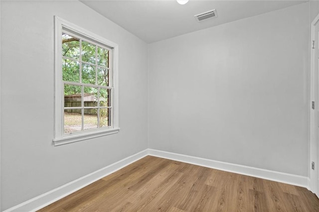 empty room featuring visible vents, baseboards, and wood finished floors