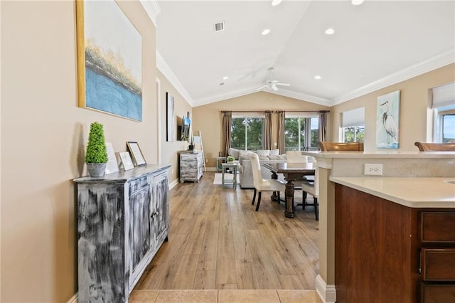 kitchen featuring visible vents, ornamental molding, open floor plan, vaulted ceiling, and light countertops