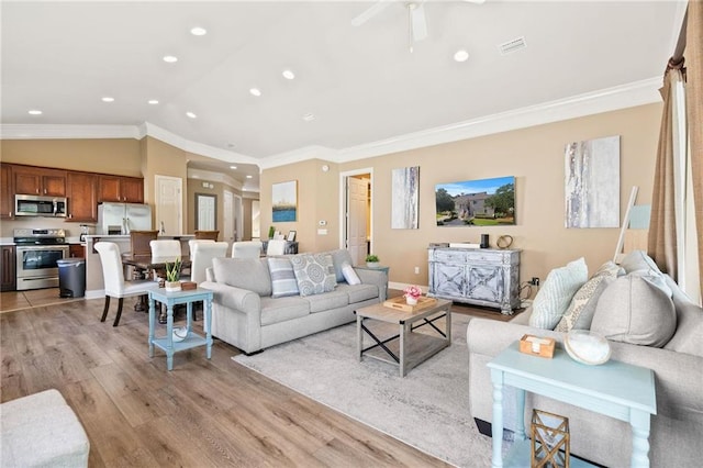 living room featuring light wood finished floors, visible vents, lofted ceiling, crown molding, and recessed lighting