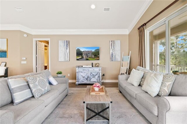 living room with ornamental molding, wood finished floors, visible vents, and baseboards