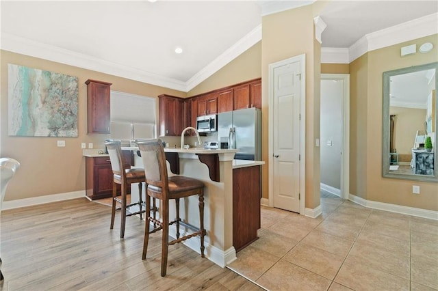 kitchen featuring a kitchen island, light countertops, ornamental molding, appliances with stainless steel finishes, and a kitchen bar