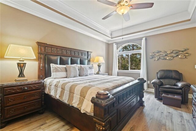 bedroom with wood-type flooring, a raised ceiling, and crown molding