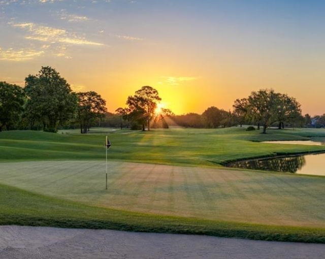 view of property's community with view of golf course, a water view, and a yard