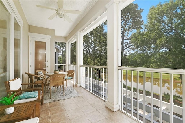 sunroom with ceiling fan and a water view