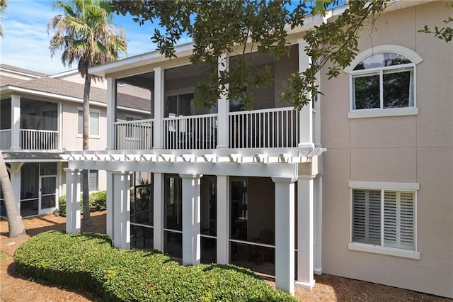 rear view of house with a balcony and stucco siding