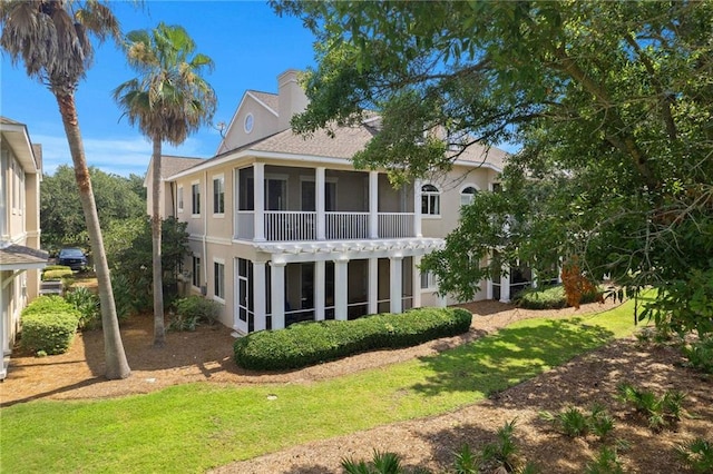 back of house featuring a sunroom, a chimney, and stucco siding