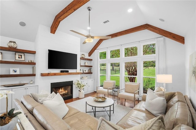 living room featuring a large fireplace, ceiling fan, light hardwood / wood-style flooring, and lofted ceiling with beams