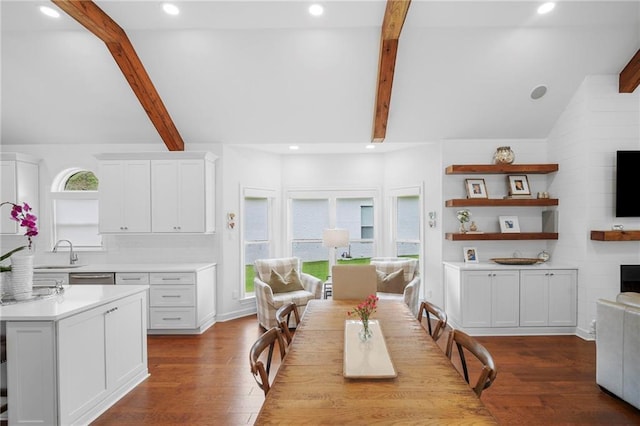 dining room with sink, light hardwood / wood-style floors, and beamed ceiling