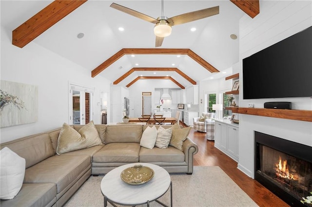 living room featuring dark wood-type flooring, beam ceiling, high vaulted ceiling, and ceiling fan