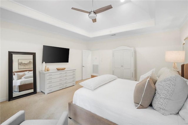 carpeted bedroom featuring ceiling fan, a tray ceiling, and crown molding