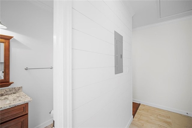 bathroom with wood-type flooring, electric panel, vanity, and crown molding