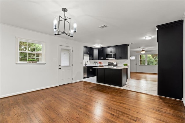 3510 Zimlich Ave, Mobile, AL 36608 - kitchen with appliances with stainless steel finishes, dark cabinets, open floor plan, light countertops, and a chandelier