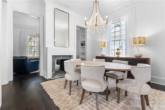 205 George St, Mobile, AL 36604 - dining space with a chandelier, dark wood finished floors, a fireplace, built in shelves, and crown molding