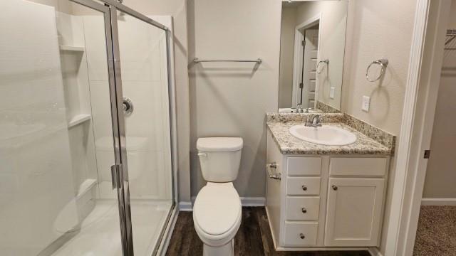 bathroom featuring a stall shower, vanity, toilet, and baseboards