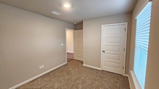 unfurnished bedroom with baseboards, visible vents, and carpet flooring