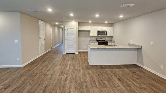 kitchen with dark wood finished floors, stainless steel appliances, visible vents, white cabinetry, and a peninsula