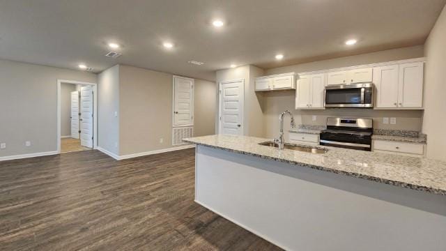 kitchen featuring light stone counters, dark wood-style flooring, appliances with stainless steel finishes, white cabinets, and a sink