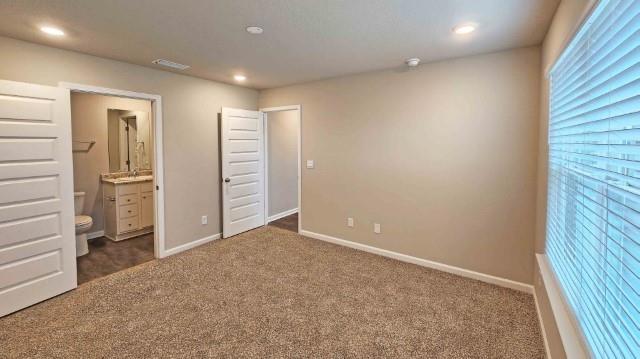 unfurnished bedroom featuring carpet floors, ensuite bath, baseboards, and recessed lighting