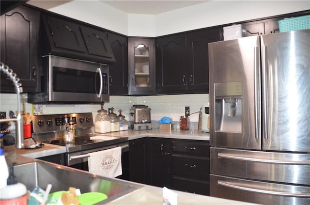 kitchen with glass insert cabinets, appliances with stainless steel finishes, light countertops, and decorative backsplash