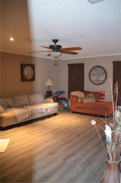 living room with a textured ceiling, ceiling fan, wood finished floors, and crown molding