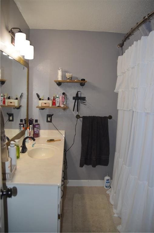 bathroom featuring baseboards, a textured ceiling, and vanity