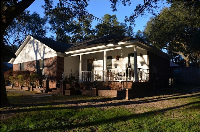 exterior space featuring covered porch, brick siding, and a lawn