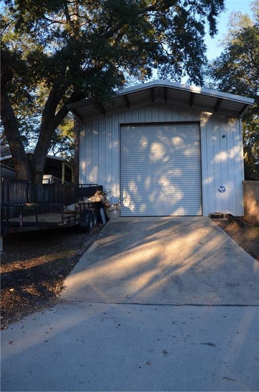 detached garage featuring driveway and fence