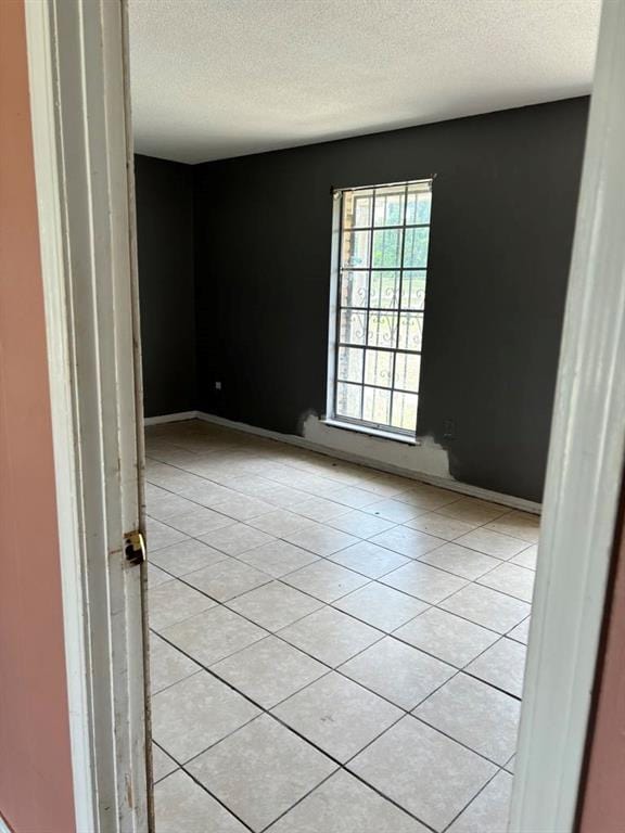 tiled spare room featuring a textured ceiling