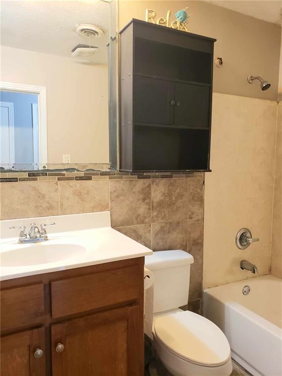 full bathroom with vanity, toilet, tile walls, and bathing tub / shower combination