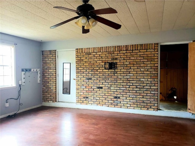 empty room featuring brick wall, ceiling fan, and hardwood / wood-style floors