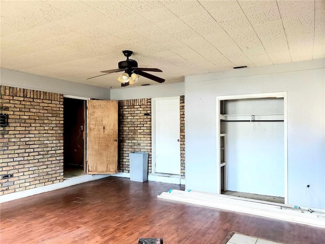 unfurnished bedroom with brick wall, ceiling fan, and hardwood / wood-style flooring