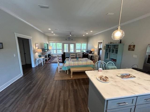 interior space with a kitchen island, ceiling fan, dark wood-type flooring, crown molding, and hanging light fixtures