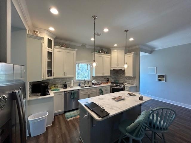 kitchen with white cabinets, pendant lighting, tasteful backsplash, and stainless steel appliances