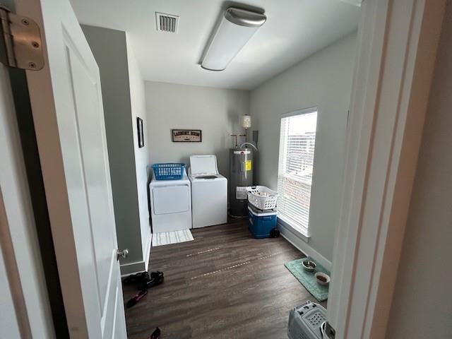 clothes washing area with dark hardwood / wood-style floors, electric water heater, and washing machine and clothes dryer