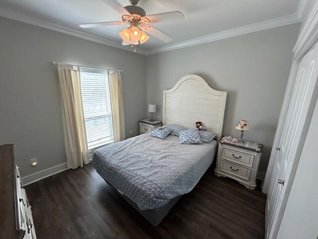 bedroom with ceiling fan, crown molding, and dark wood-type flooring