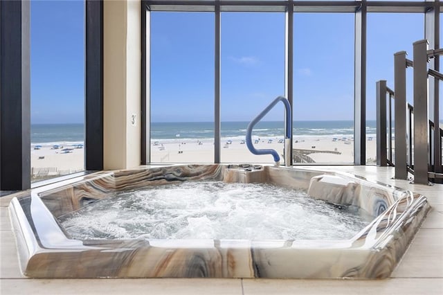 bedroom featuring multiple windows, a water view, and a view of the beach