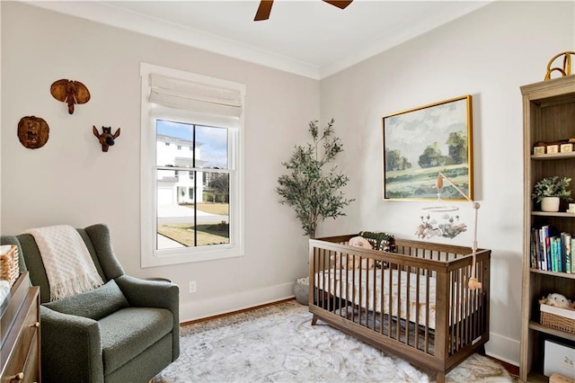 bedroom featuring baseboards, a ceiling fan, wood finished floors, crown molding, and a nursery area