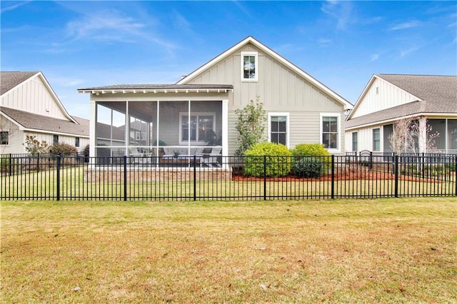 rear view of house with board and batten siding, a sunroom, fence, and a lawn