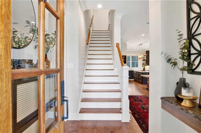 stairway with wood finished floors and recessed lighting