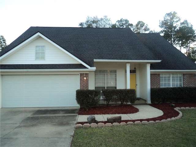 view of front facade featuring a garage, roof with shingles, concrete driveway, and brick siding