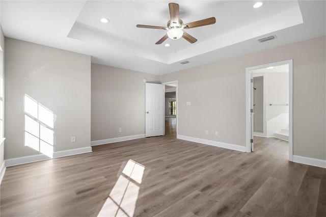 unfurnished bedroom with a raised ceiling, ceiling fan, and wood-type flooring