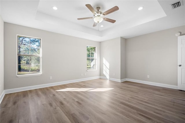 unfurnished room with a tray ceiling, ceiling fan, and wood-type flooring