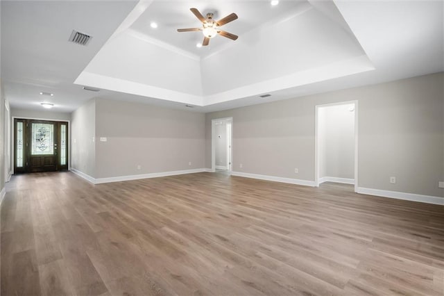 unfurnished living room with ceiling fan, a raised ceiling, and light hardwood / wood-style flooring