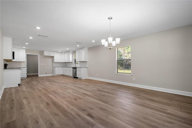 unfurnished living room with sink, an inviting chandelier, and hardwood / wood-style flooring