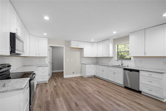 kitchen with light stone countertops, sink, appliances with stainless steel finishes, white cabinets, and light wood-type flooring