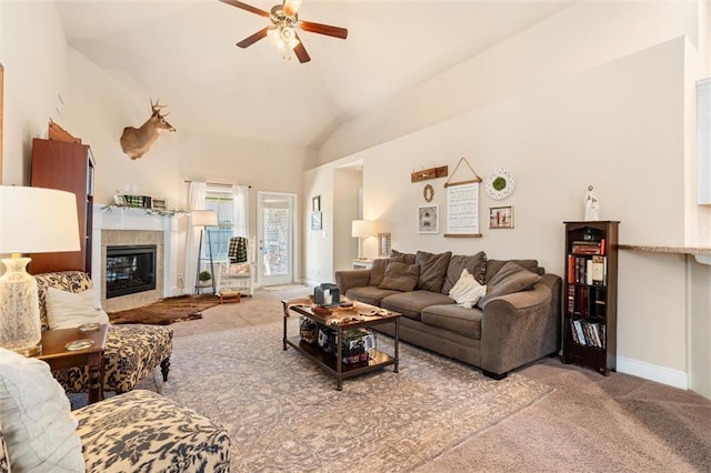 living area with ceiling fan, baseboards, carpet, vaulted ceiling, and a tile fireplace